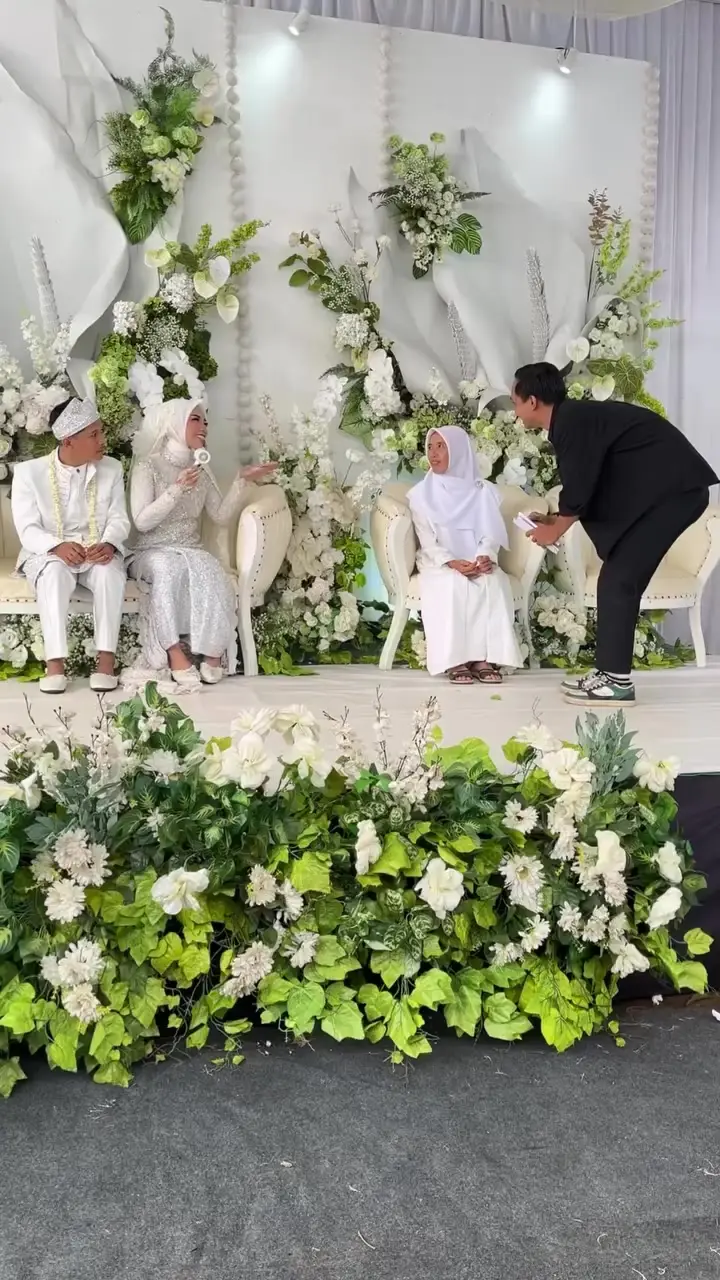 Keluarga duduk di pelaminan bunga putih sementara kru JOIEA membantu merapikan posisi
