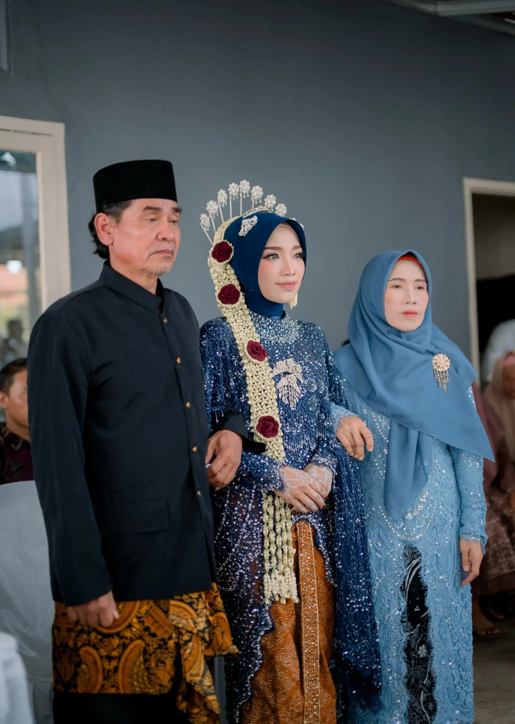 Pengantin wanita berbusana Jawa biru diapit ayah dan ibunya sebelum prosesi panggih