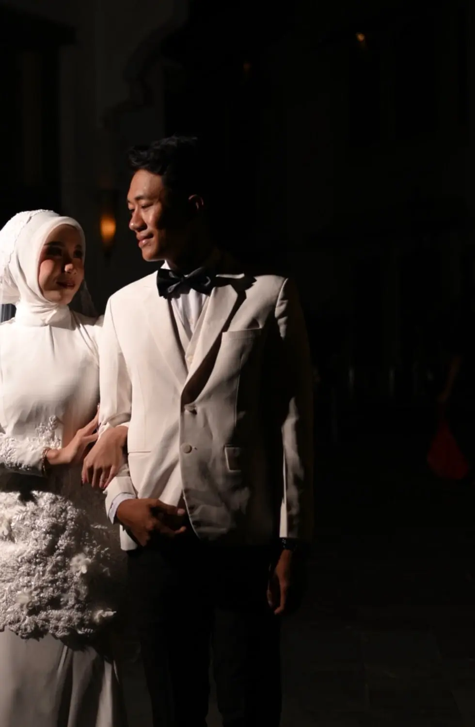 Pasangan prewedding berjalan bergandengan dalam cahaya malam