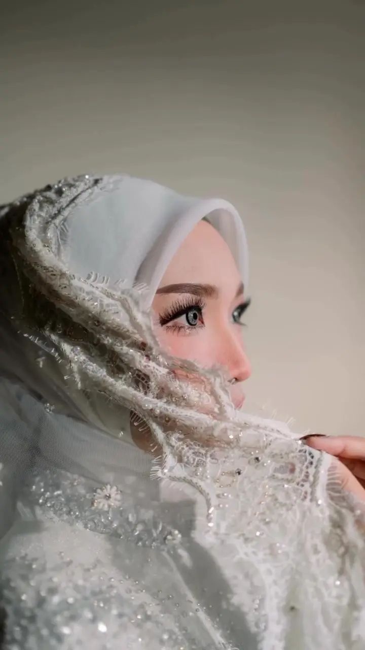 Pengantin wanita berkerudung putih berpayet dilihat dari samping